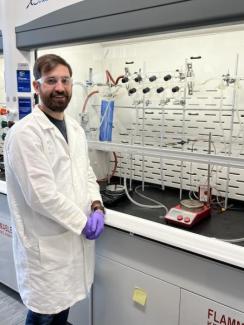 Photo of speaker Nathan Thacker standing by a fume hood in an organic chemistry lab