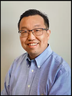 Image is Asian man wearing glasses and a blue shirt