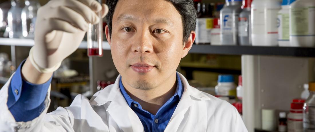 Jin Xie holds a tube in his lab